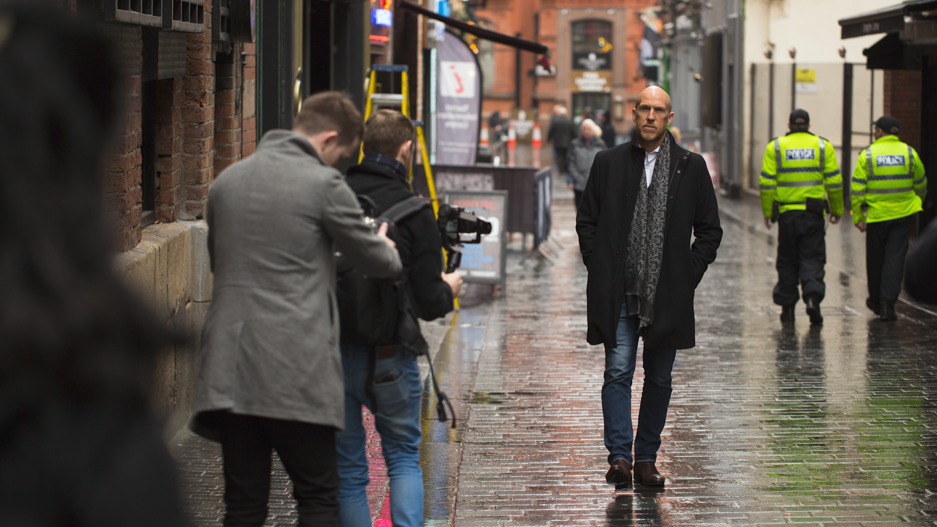 Two camera men are filming a man walking through a street in Liverpool.