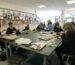 A group of school kids sat at a large table in an art class.